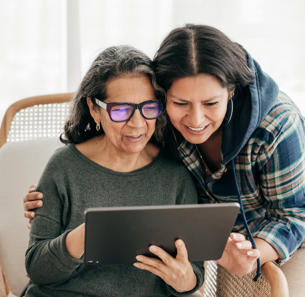 senior woman looking at her ipad with her adult daughter