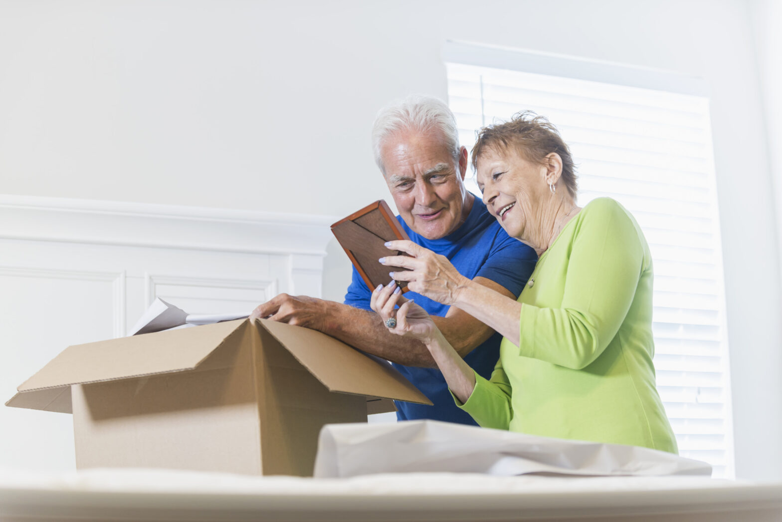 Senior couple looking at photo in a picture frame while packing a cardboard box