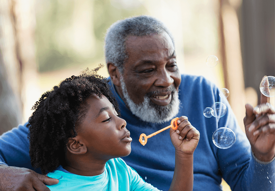 Senior man blowing bubbles with young grandson